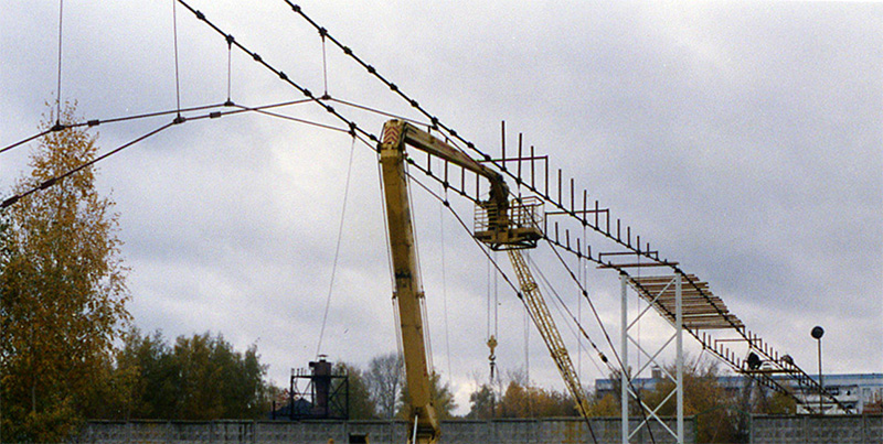 Под руководством генерального конструктора и автора СТЮ Анатолия Юницкого на испытательном полигоне осуществляется монтаж рельсо-струнной путевой структуры на строящемся стенде СТЮ Путевая структура